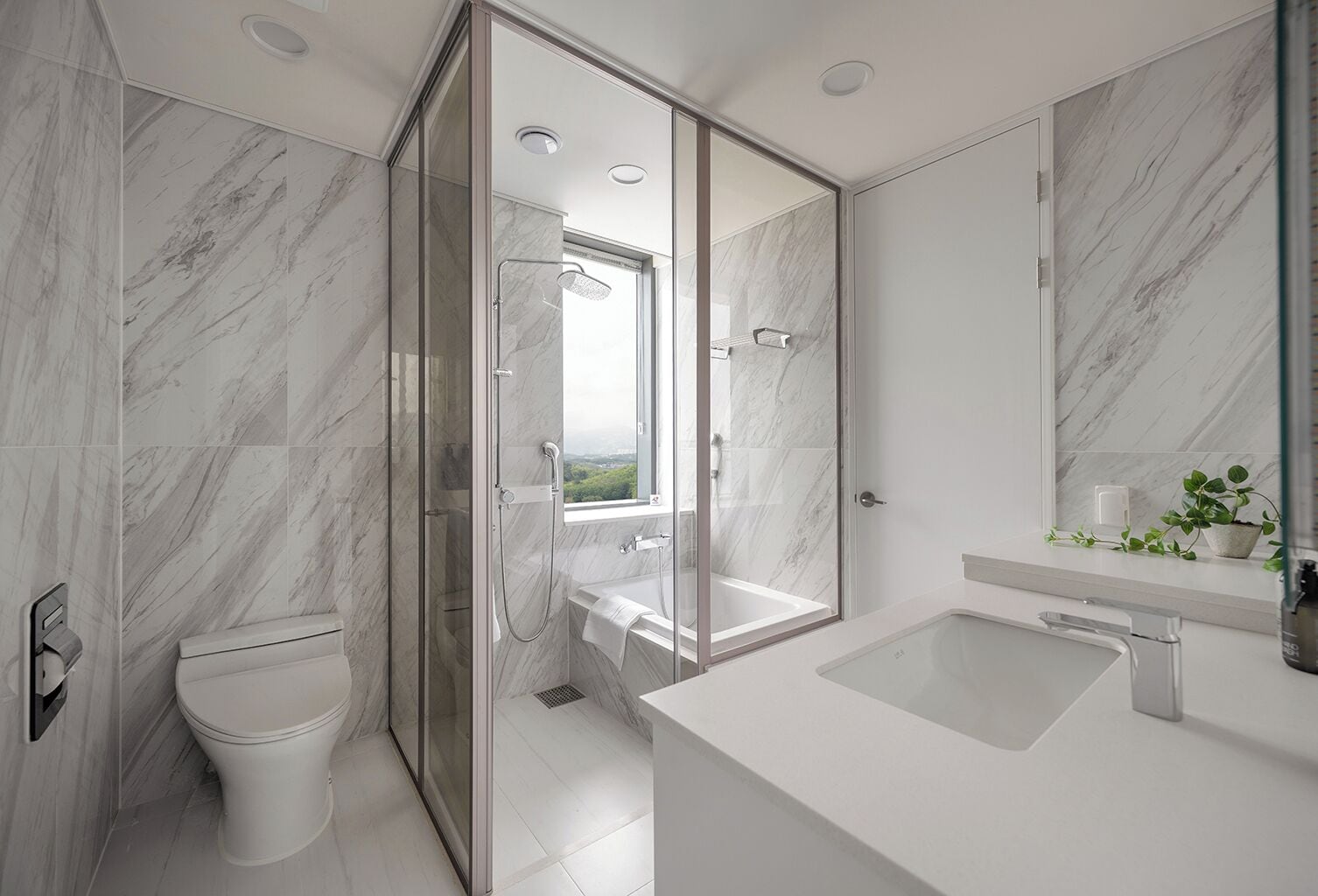 A modern bathroom with a glass-enclosed shower, a white toilet, a bathtub, and a large mirror.