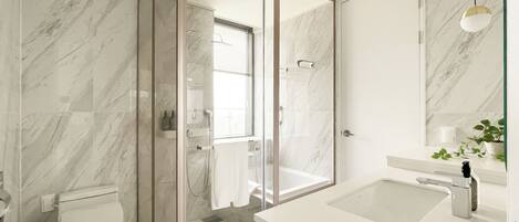 A modern bathroom with a glass-enclosed shower, a white sink, and a marble-tiled wall.