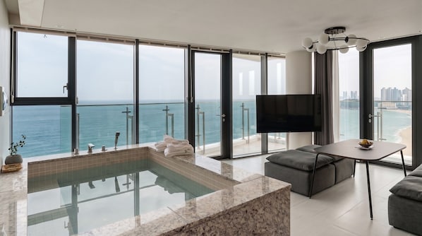 A modern living room with a large TV, a seating area, and a view of the ocean. - Plott The Gak Yangyang (Yangyang)
