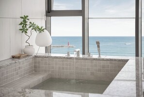 A modern bathroom with a large bathtub, a potted plant, and a view of the sea. - Plott The Gak Yangyang (Yangyang)