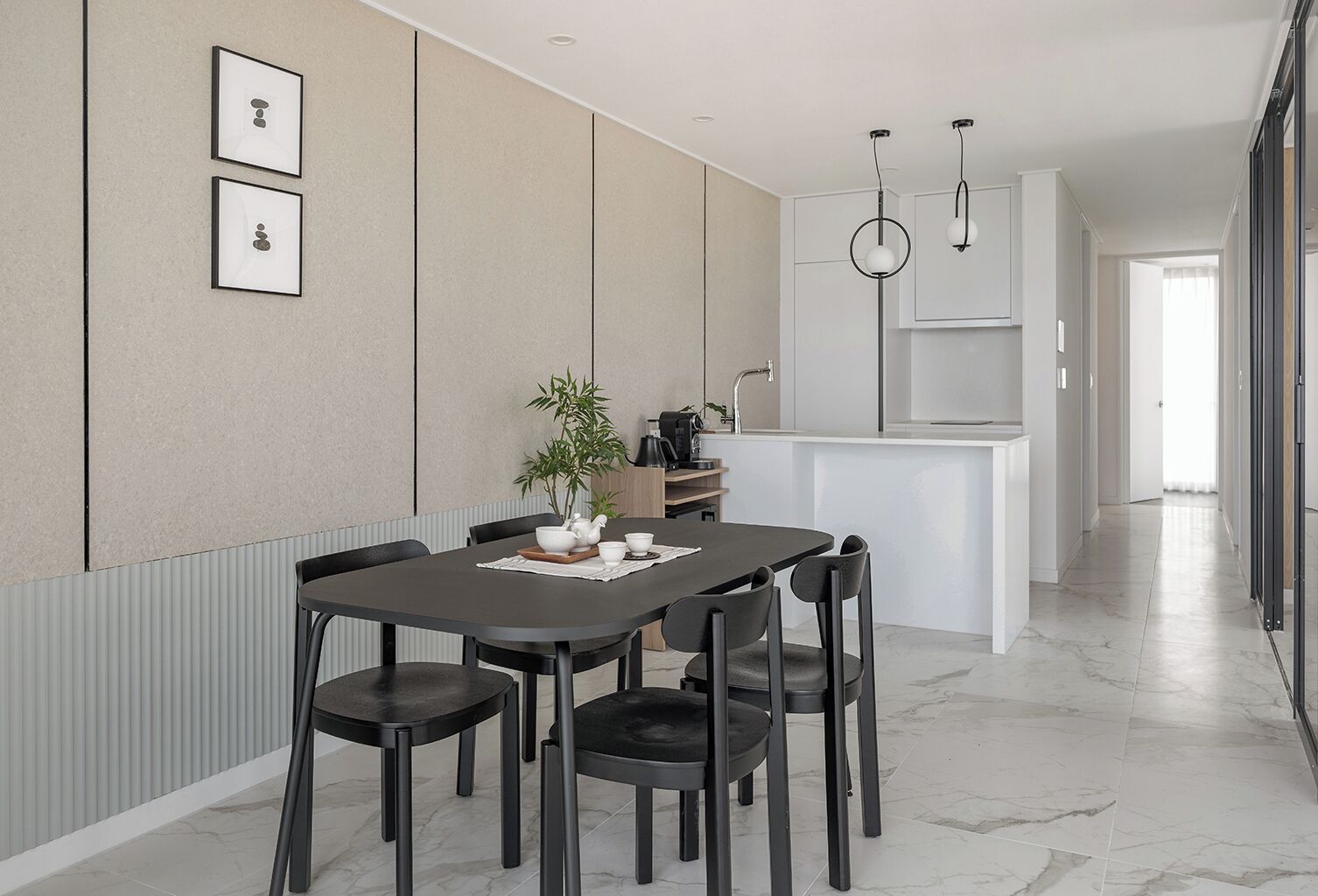 A modern kitchen with a dining area, featuring a marble floor, a central island, and pendant lighting.