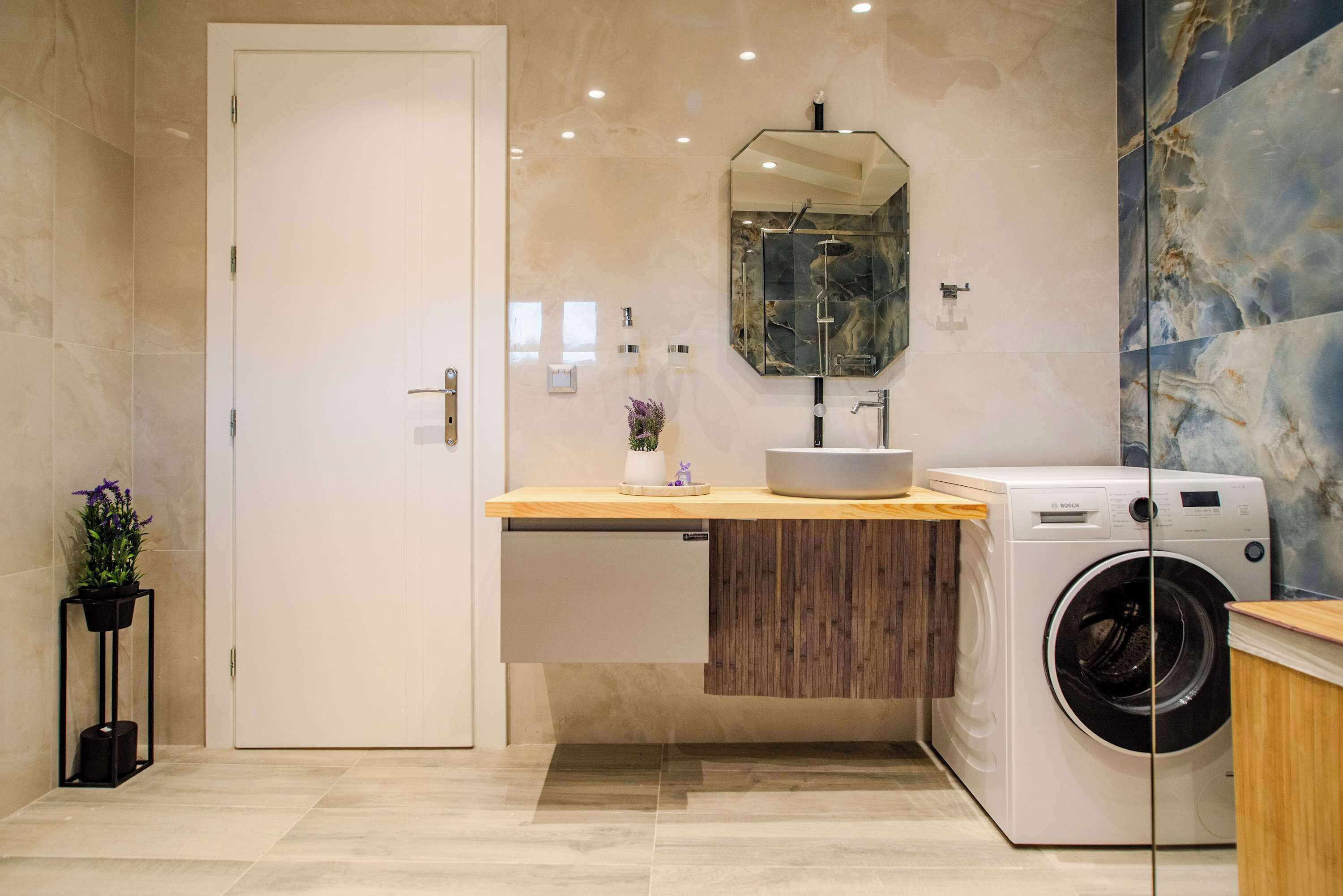 Un bagno moderno con lavatrice integrata, un mobile bagno in legno e un ampio specchio.