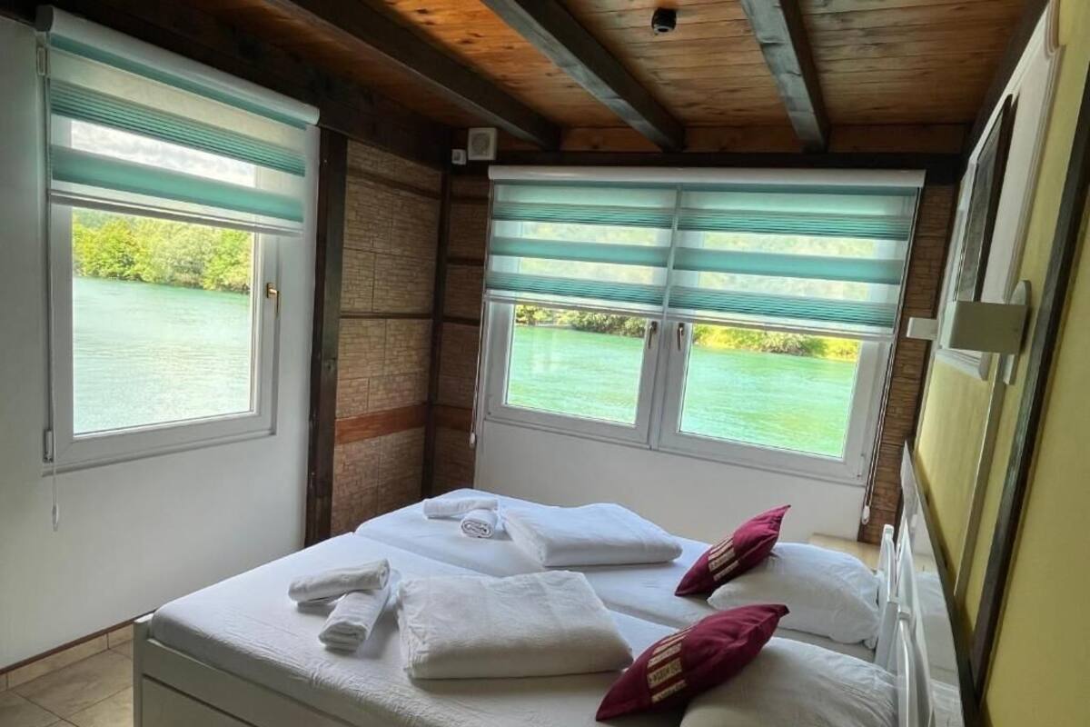 Un dormitorio con dos camas, vista a un cuerpo de agua y techo de madera.
