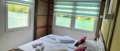 Un dormitorio con dos camas, vista a un cuerpo de agua y techo de madera.