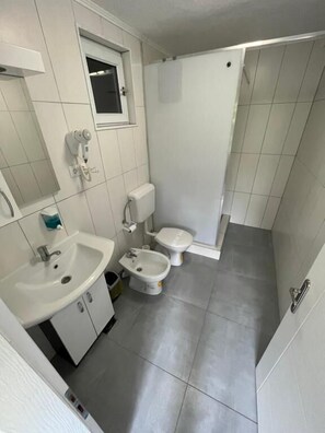 A bathroom with a sink, two toilets, a bidet, and a shower. - Hotel Neron i River View (Bihać)