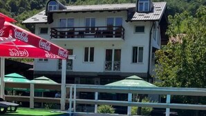 Uma piscina com vista para um edifício com varandas e um guarda-sol com a marca Coca-Cola.