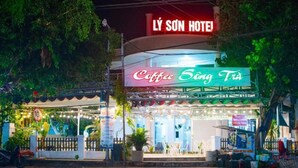 Ένα ξενοδοχείο με το όνομα «LY SÔN HOTEL» και μια επιγραφή νέον που αναγράφει «Coffee Sông Trì».