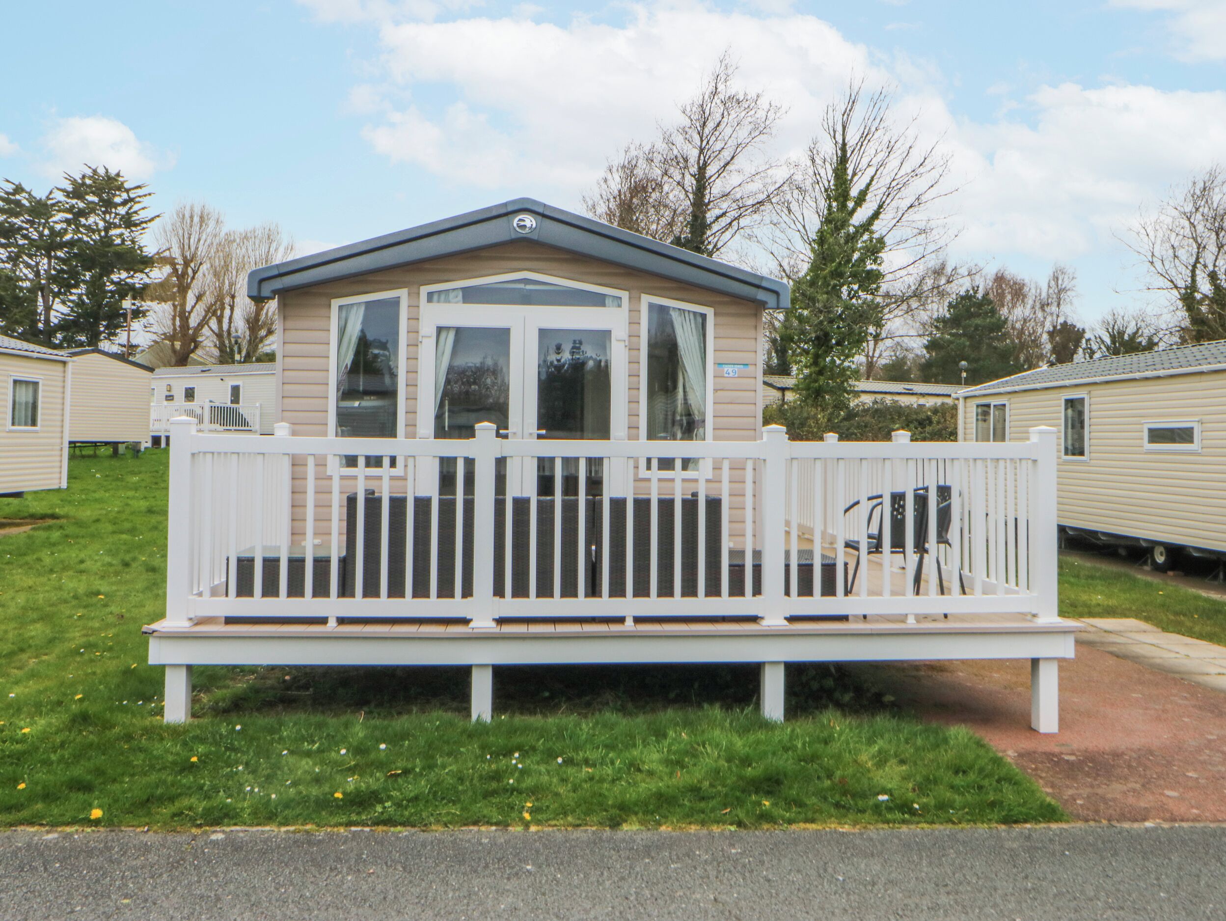 A mobile home with a fenced deck and a small porch.