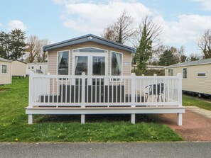 A mobile home with a fenced deck and a small porch. - 49 Cader Idris, Hafan-y-mor Holiday Park (Pwllheli)