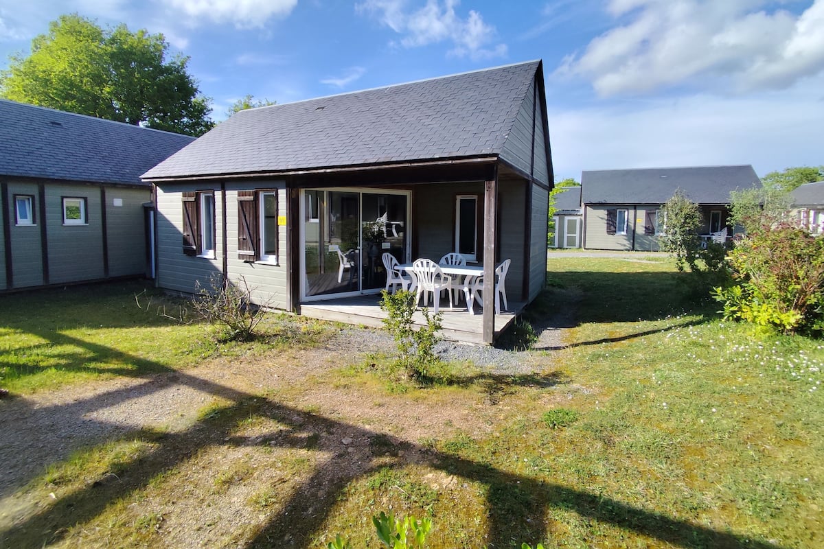 Une petite maison avec une véranda, une table et des chaises.