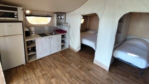 A compact, well-organized tent with a kitchenette, a bed, and a small bathroom.