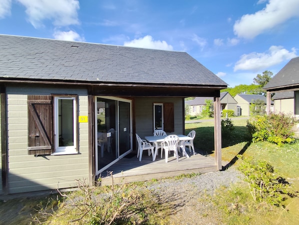 A small building with a porch, a table with chairs, and a sliding glass door. - Village Cévéo de MesquerPays de Guérande (Mesquer)