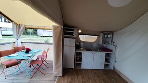 A compact kitchen with a refrigerator, microwave, and sink, adjacent to a dining area with a table and chairs.
