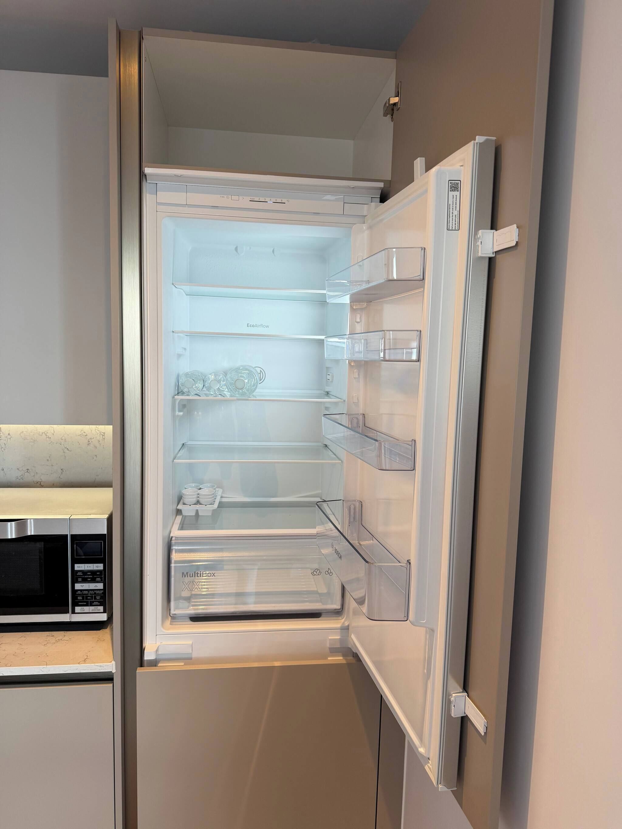 An open refrigerator with multiple shelves and a built-in microwave.