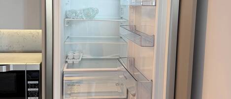An open refrigerator with multiple shelves and a built-in microwave.