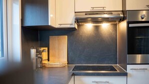 Eine moderne Küche mit Einbauherd, Edelstahlgeräten und einer Holzschneidebrett.