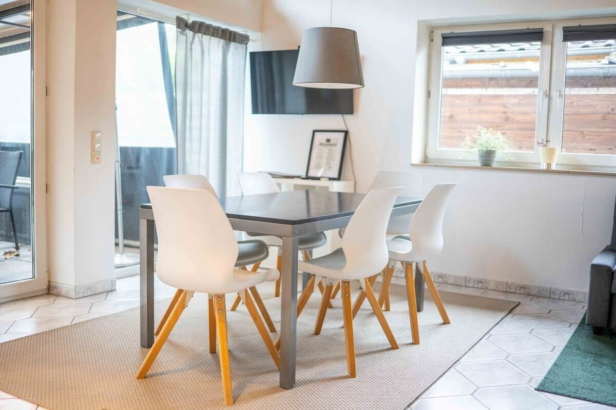 A dining area with a table, chairs, a lamp, and a window with a view.