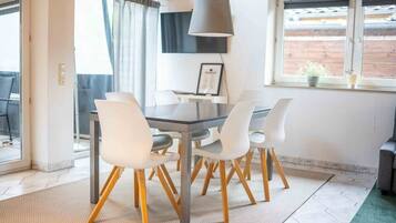 A dining area with a table, chairs, a lamp, and a window with a view.