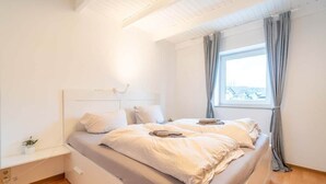 Ein Schlafzimmer mit Bett, Nachttisch und einem Fenster mit Vorhängen.