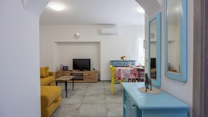 Una sala de estar con sofá, televisor y comedor con mesa y sillas.