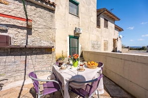 Ein Balkon mit einem Frühstückstisch, komplett mit Croissants, einer Kaffeekanne und einer Vase mit Blumen.