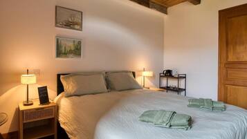 A bedroom with a bed, two bedside lamps, a nightstand, a shelf with toiletries, and a door.