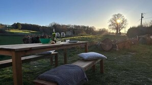 Ein Holztisch mit Bank, eine Schüssel, eine Weinflasche und ein Glas.
