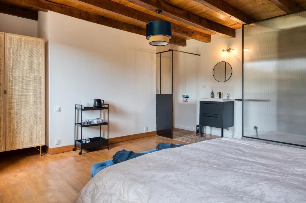 Un dormitorio con cama, armario, repisa con vasos, lámpara colgante y espejo.