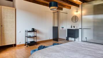 Un dormitorio con cama, armario, repisa con vasos, lámpara colgante y espejo.
