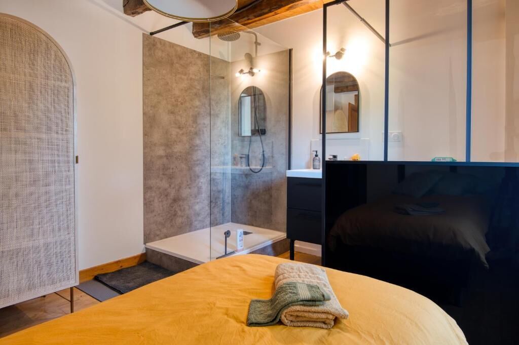 Ein modernes Badezimmer mit einer Duschkabine aus Glas, einem weißen Waschbecken und einem großen Spiegel.
