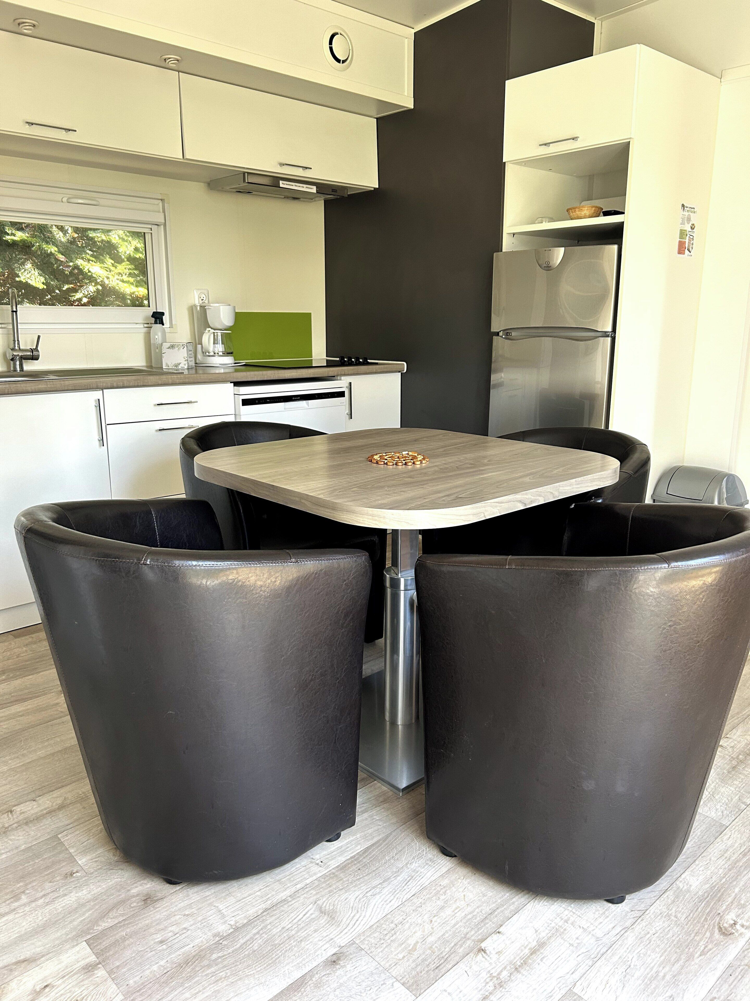 Une cuisine moderne avec une table à manger, des chaises et un réfrigérateur.