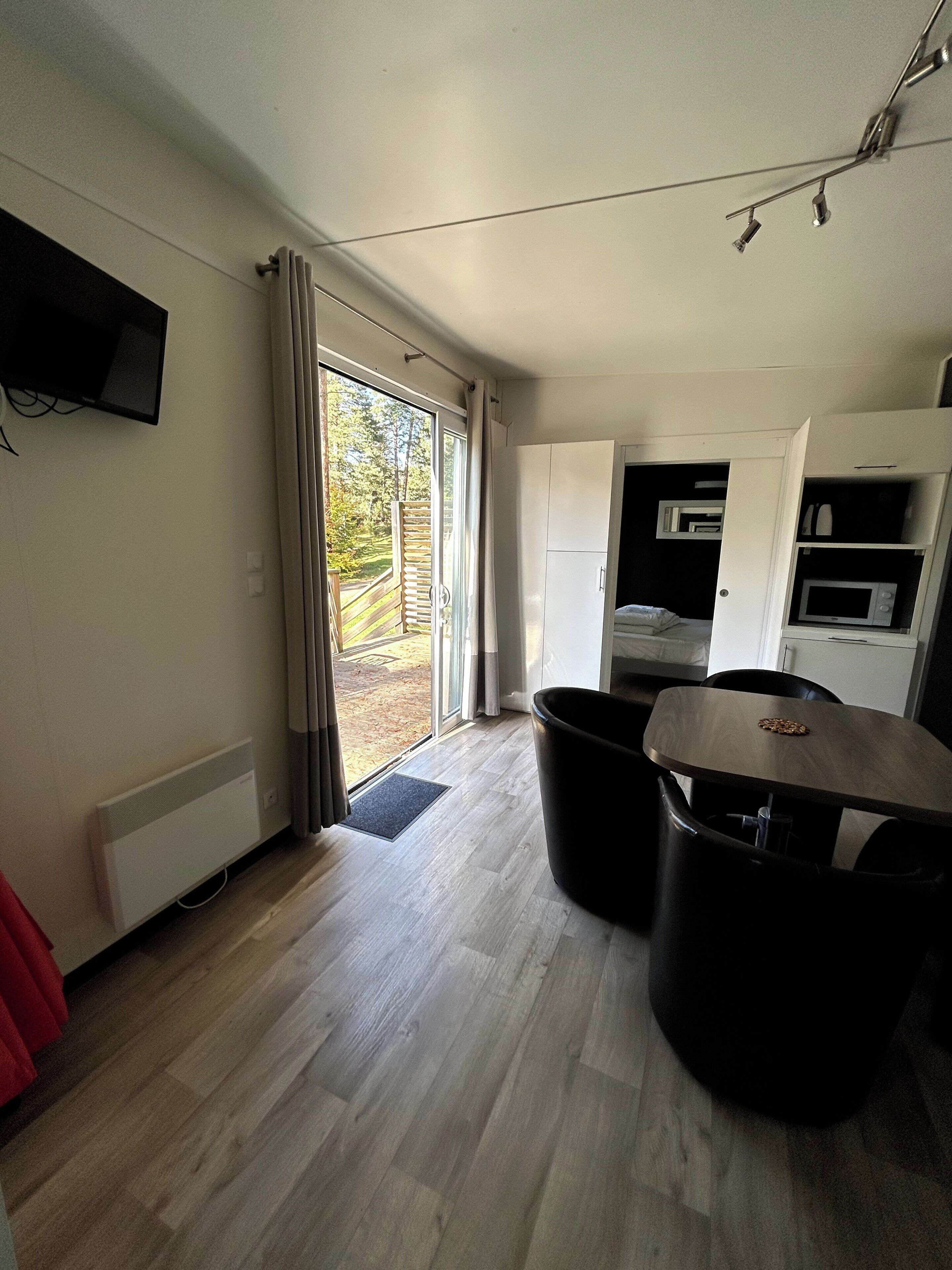 A modern kitchen with built-in appliances, a dining area with a table and chairs, and a sliding glass door leading to a balcony.