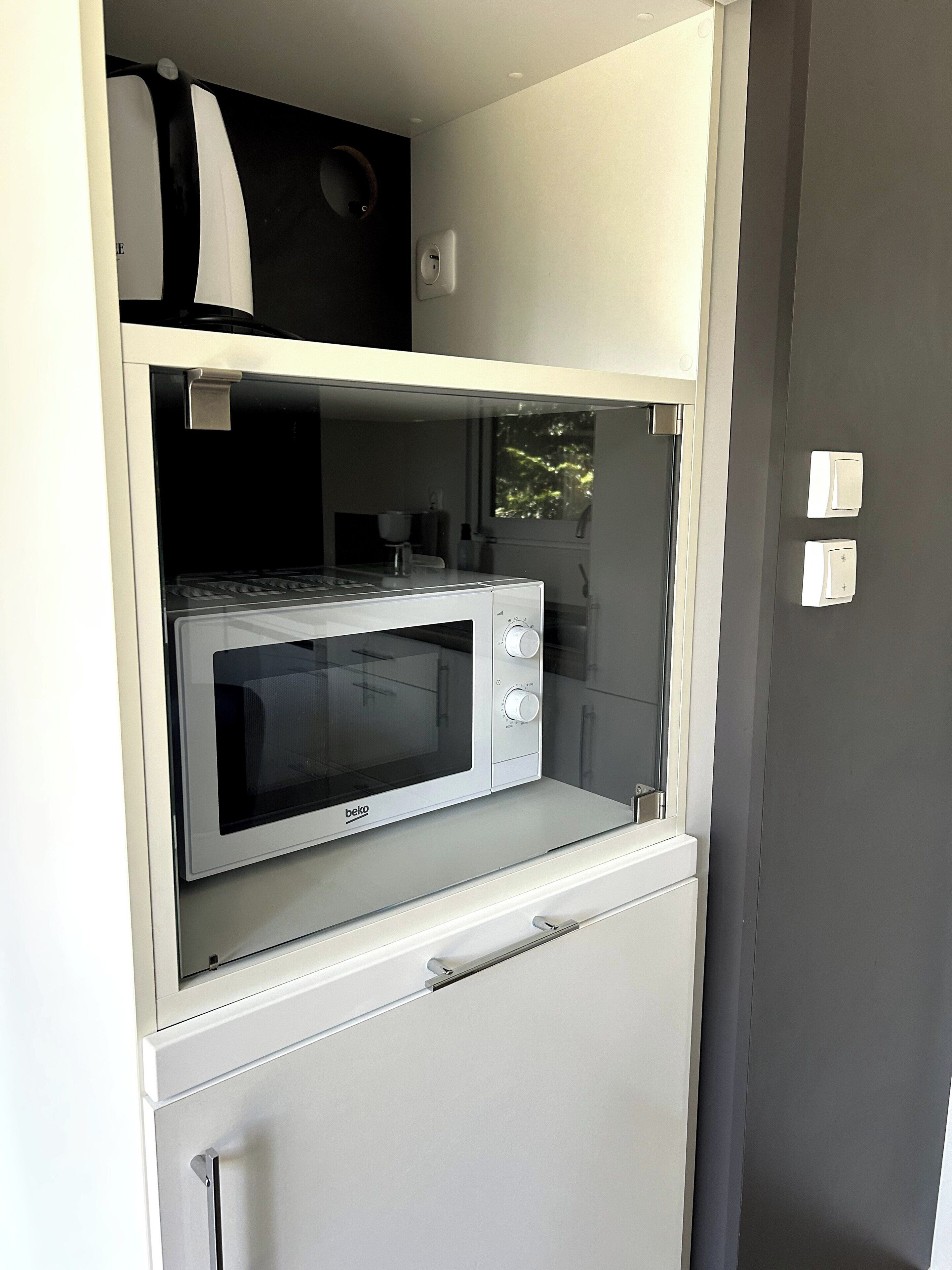 A kitchenette with a microwave, a coffee maker, and a small refrigerator.