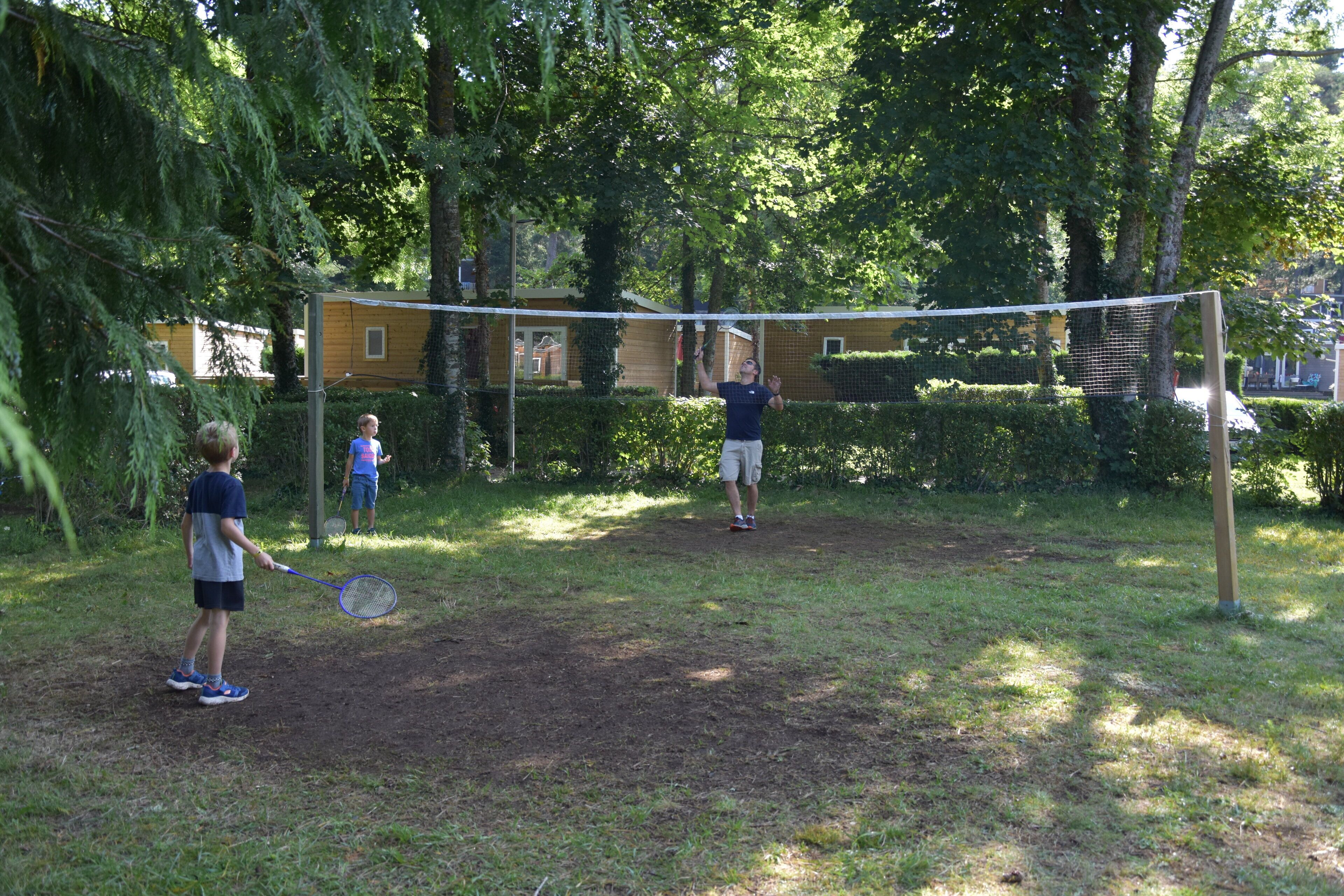 An outdoor tennis court surrounded by trees.