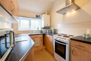 Cocina compacta con estufa, horno, microondas y ventana.