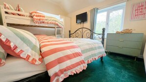 A bedroom with bunk beds, a television, a dresser, and a window with curtains. - New Forest getaway just two minutes from the station (Hampshire)