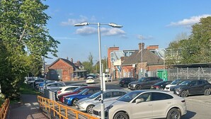 A parking area with cars, a brick pathway, and a yellow railing. - New Forest getaway just two minutes from the station (Hampshire)