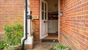 A brick exterior with a white door, a mailbox, and a small garden area with potted plants. - New Forest getaway just two minutes from the station (Hampshire)