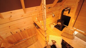 A wooden interior with a bathtub, a cat tree, and a fireplace. - Hôtel Lodge du Lac Chambon (Murol)