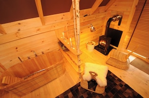 Interior de madera con una bañera, un rascador para gatos y una chimenea.