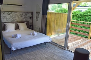Un dormitorio con una cama grande, un ventanal corredero a una terraza de madera y un papel tapiz decorado.