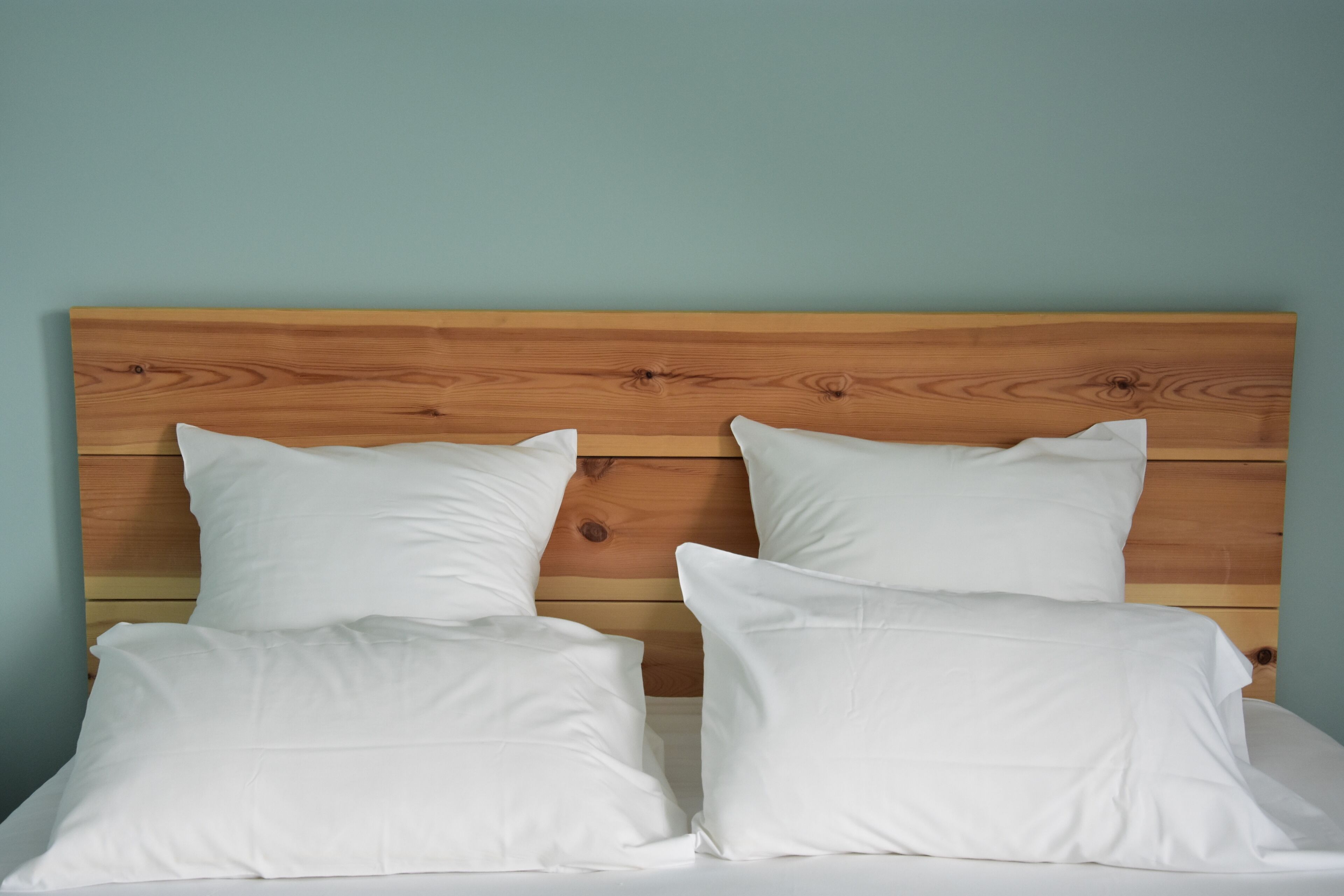 A bed with a wooden headboard and white bedding.