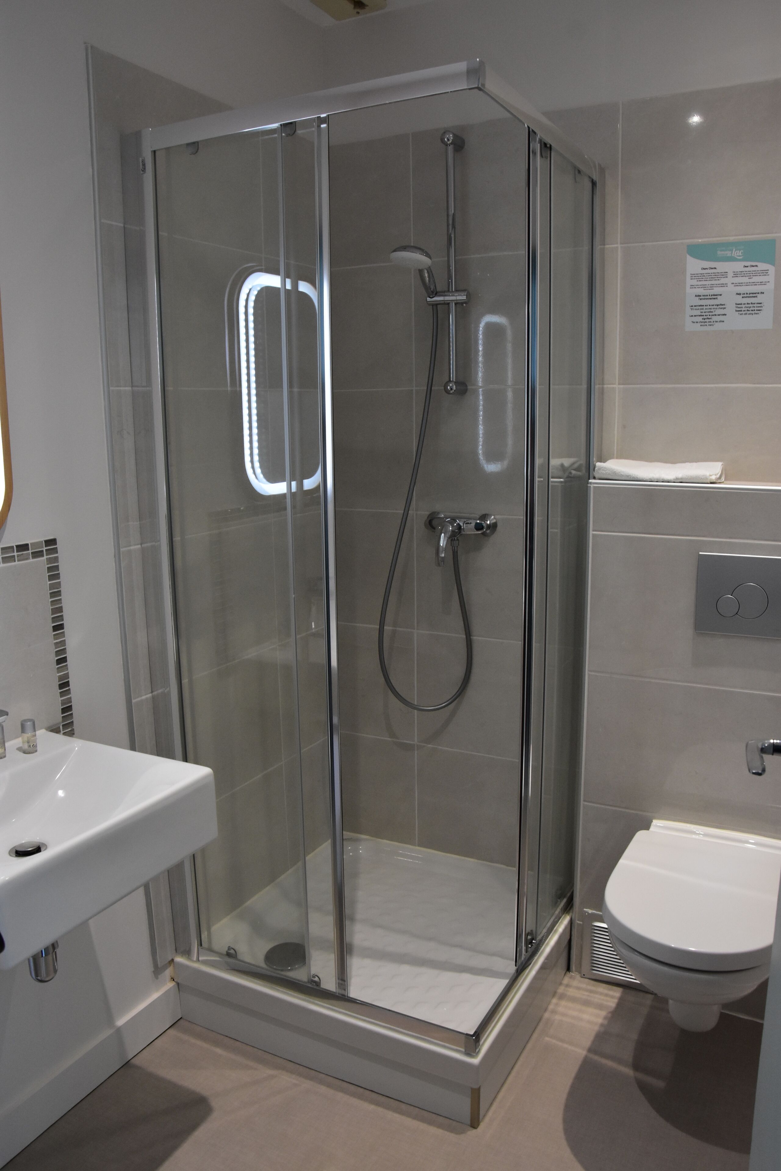 A modern bathroom with a glass-enclosed shower, a white sink, and a toilet.