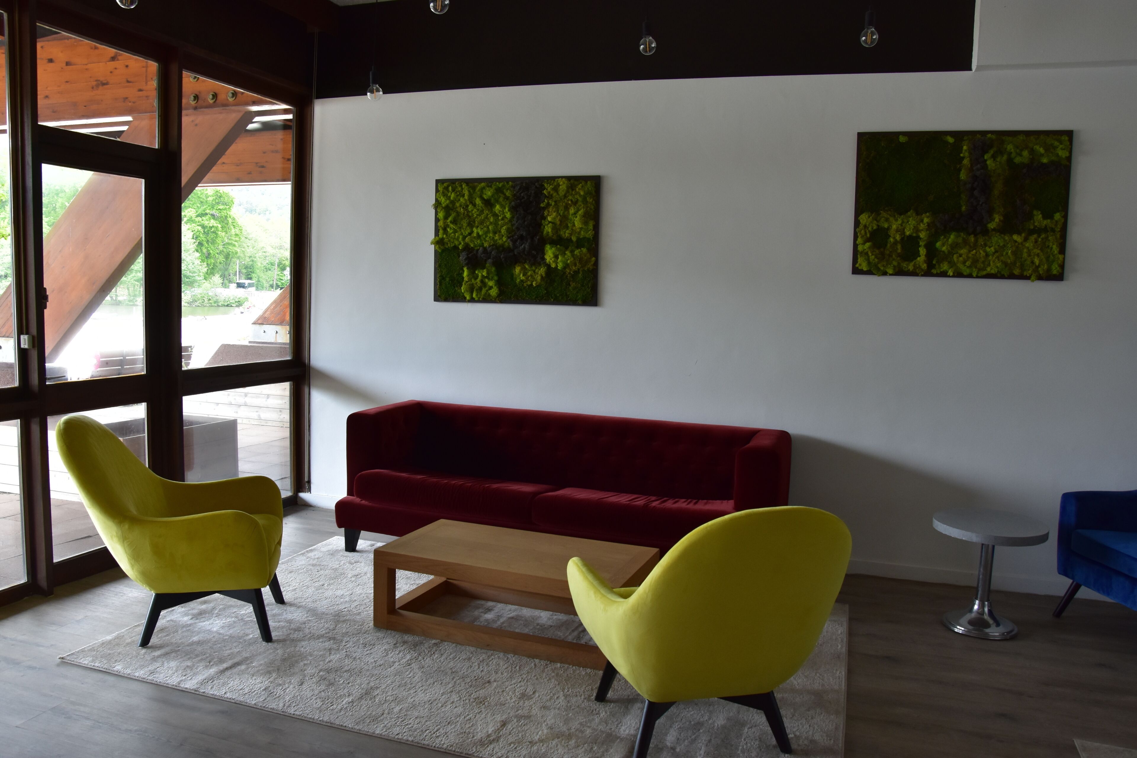 A modern interior with a red sofa, yellow chairs, and two abstract paintings on the wall.