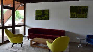 A modern interior with a red sofa, yellow chairs, and two abstract paintings on the wall.