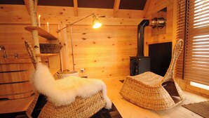 A wooden interior with a fireplace, wicker furniture, and a hanging light fixture. - Hôtel Lodge du Lac Chambon (Murol)