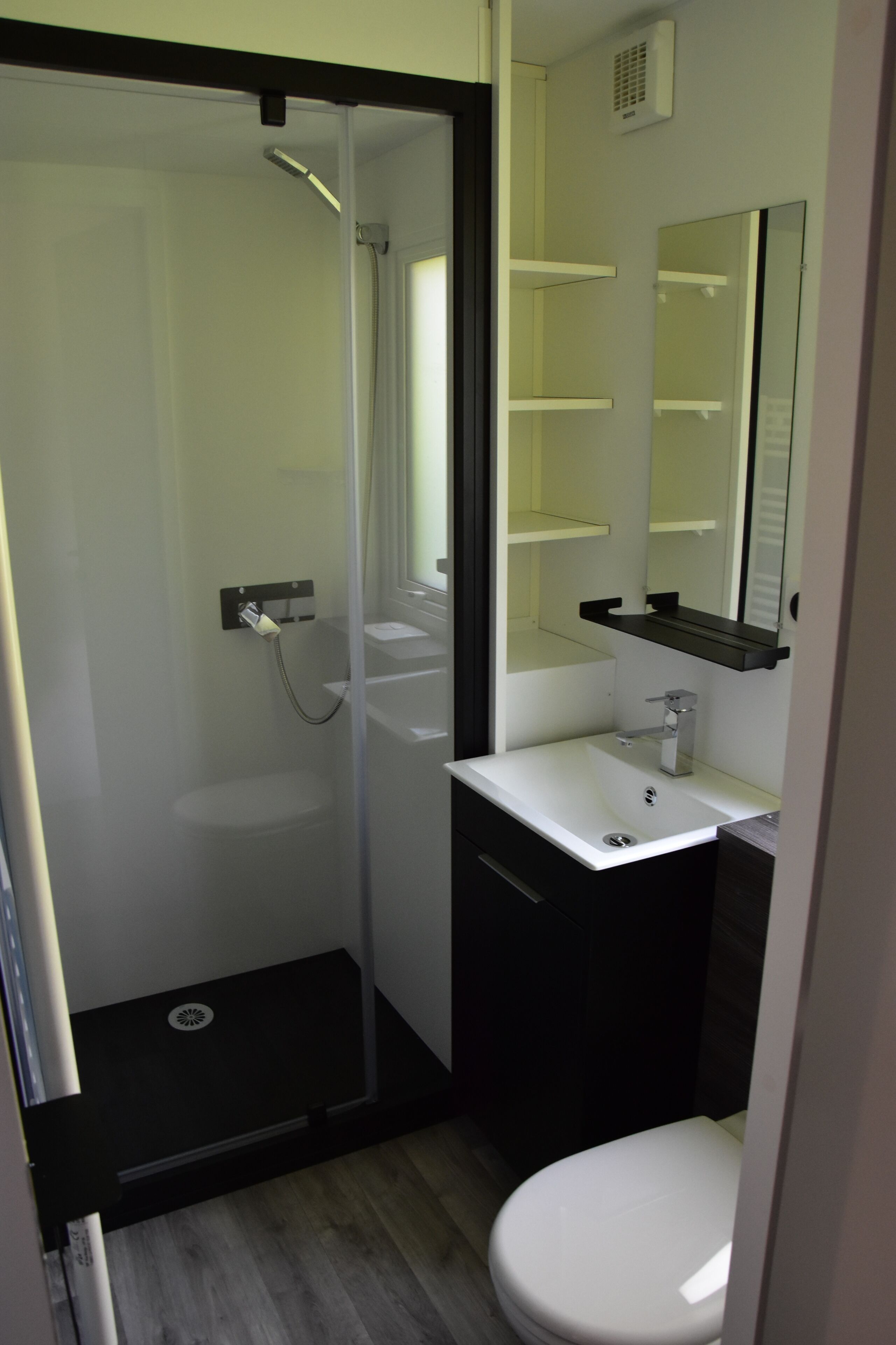 A bathroom with a glass shower enclosure, a white sink, a mirror, and a toilet.
