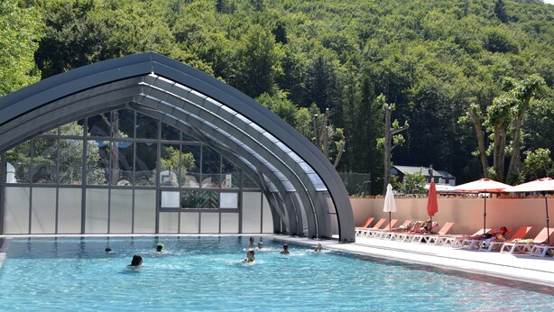 A swimming pool with a covered area, surrounded by lounge chairs and umbrellas. - Hôtel Lodge du Lac Chambon (Murol)