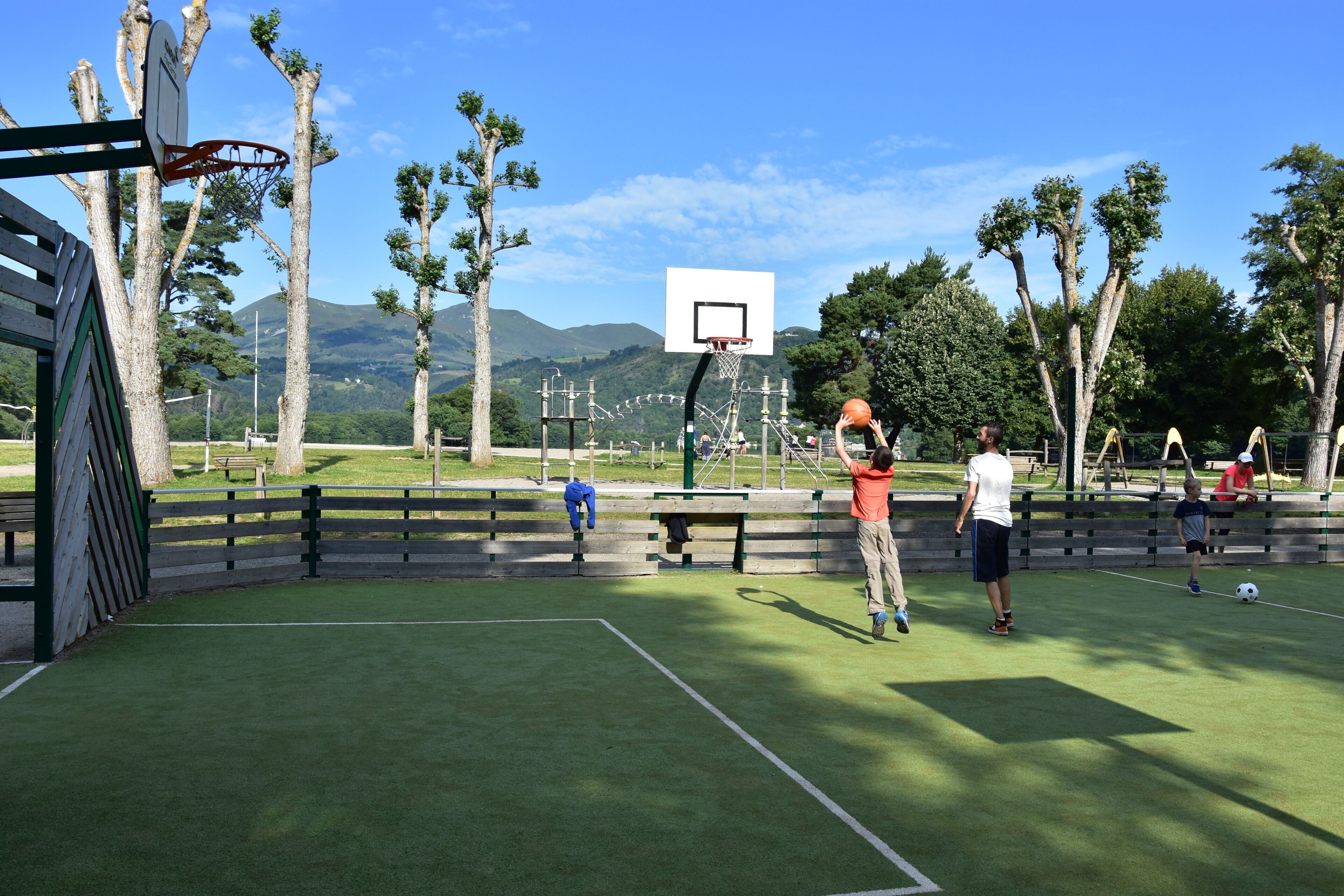 An outdoor basketball court with a net, benches, and trees in the background.