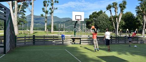An outdoor basketball court with a net, benches, and trees in the background.